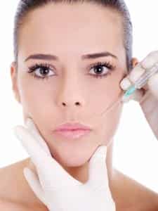 front view of a young woman's face with a syringe near her lips