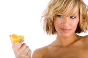 young woman with short hair looking at an orange slice in her hand