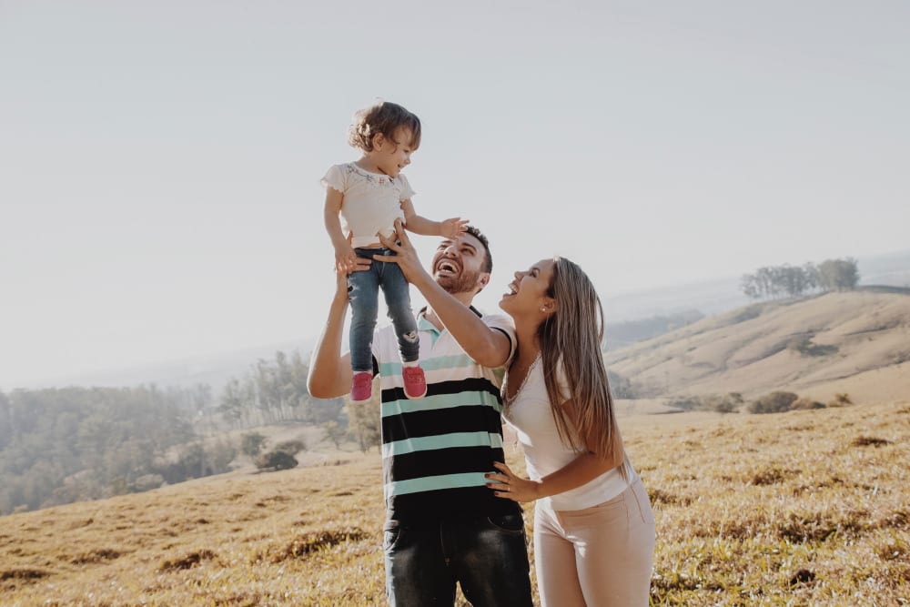 Man lifting child with her wife next to them on a beautiful landscape 