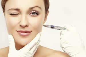 woman's face winking while receiving an injection in her cheek