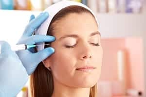 young woman during botox treatment on her temples