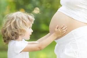 little girl touching the belly of a pregnant woman