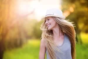 young girl in the open field smiling with a fedora