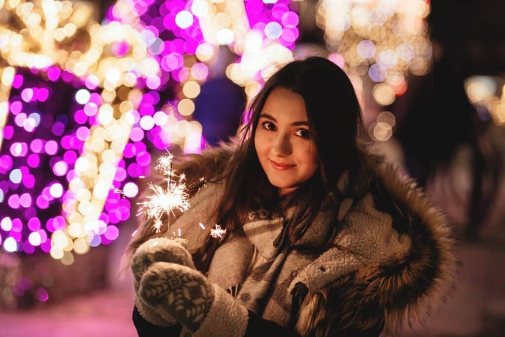 young woman in a warm coat with a sparkler in her hands