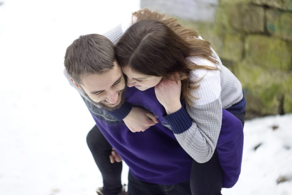 man giving a piggy back ride to his wife outdoors