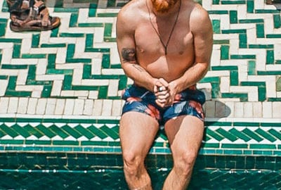 long-bearded man sitting on the edge of the pool