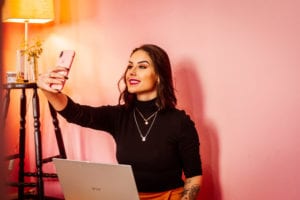 Woman in a black long sleeve shirt taking a selfie for her plastic surgery app.