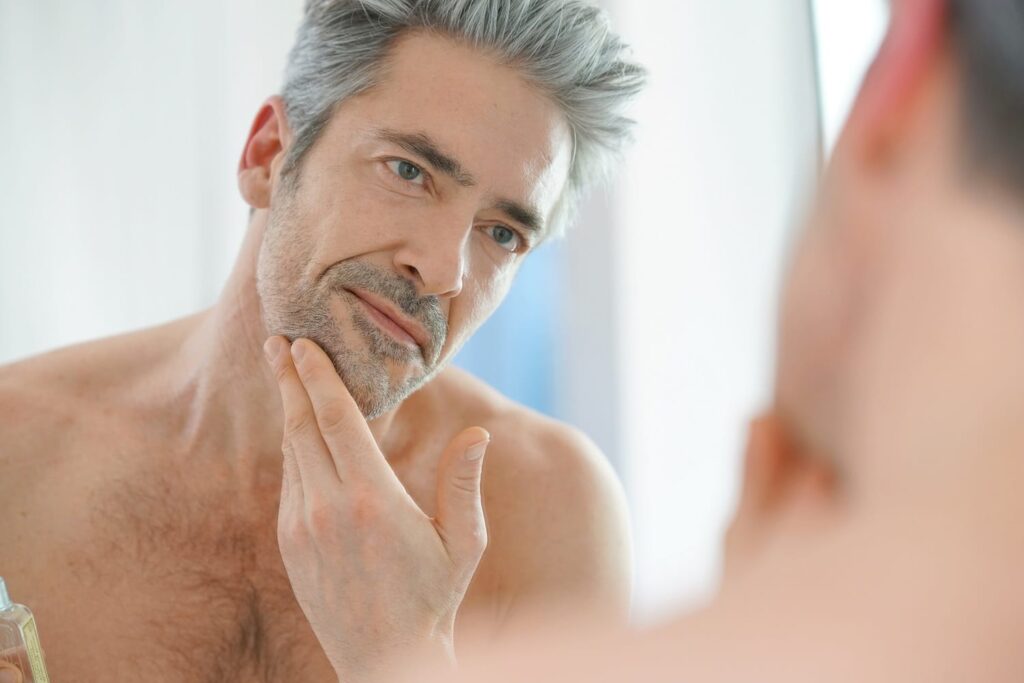 Daniel -Portrait of mature man in front of mirror applying facial cream