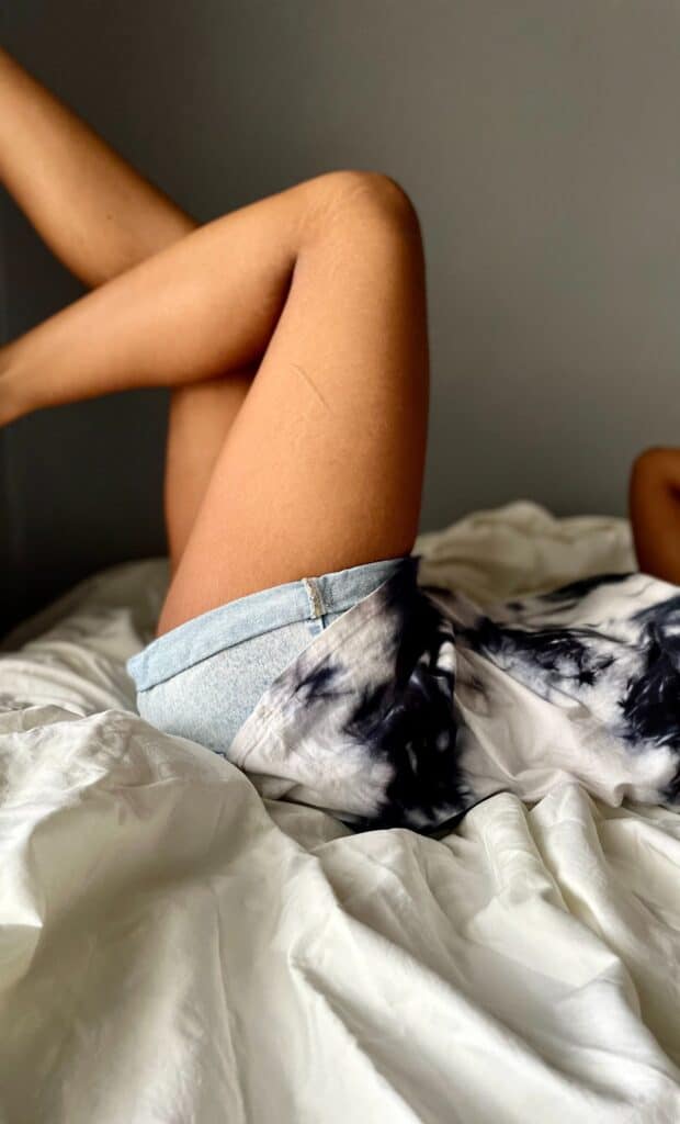 woman in jean shorts lying in bed