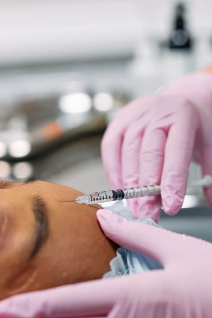 close up of needle injecting botox in forehead