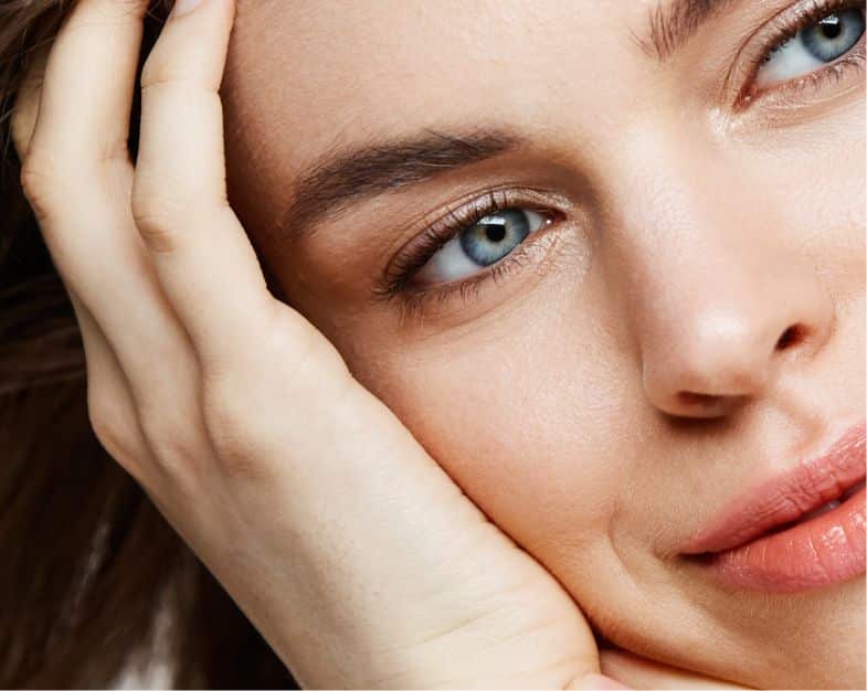 close up of a women's face, looking to the side and leaning on her hand