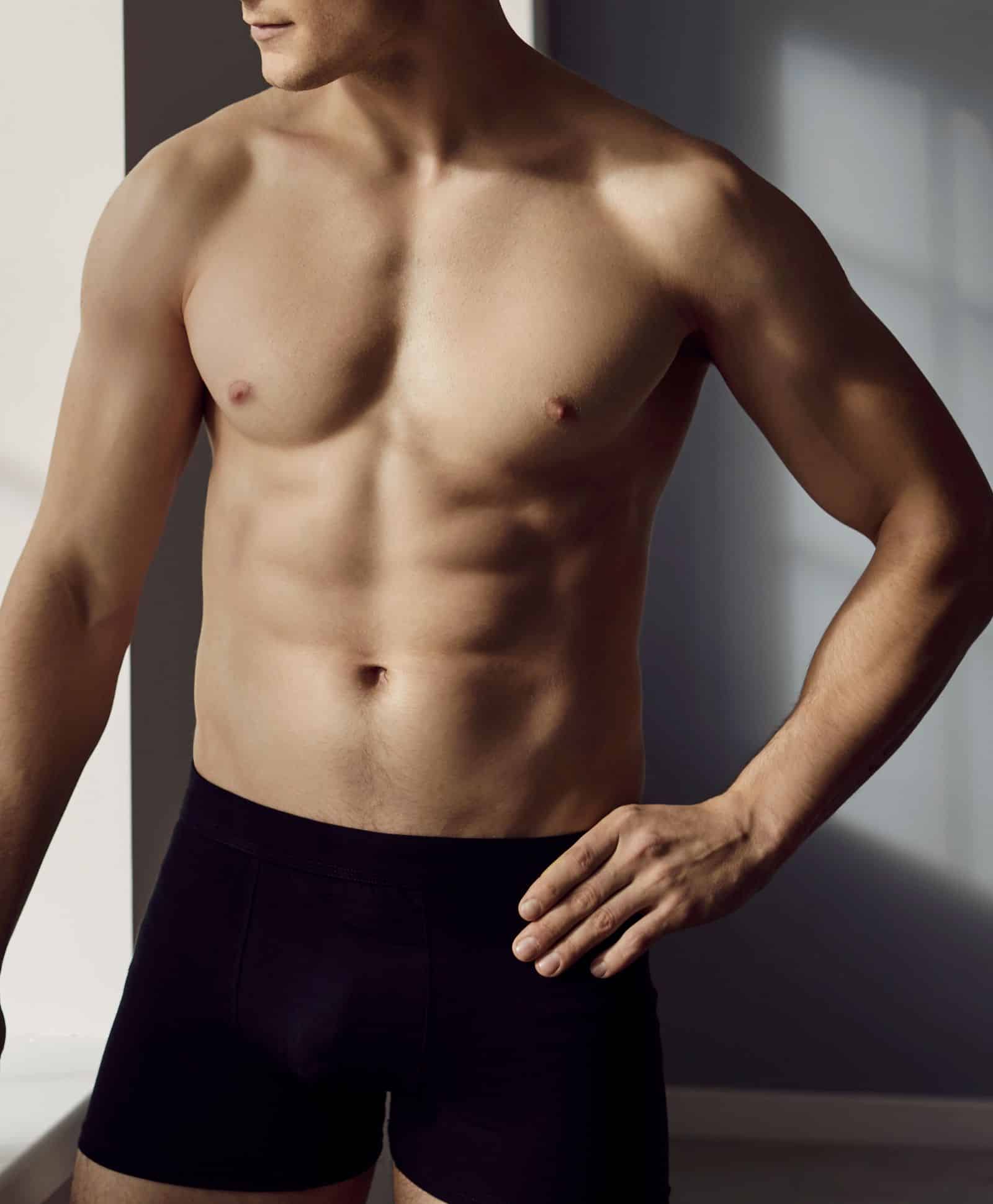 Shirtless male looking on the side in black boxers