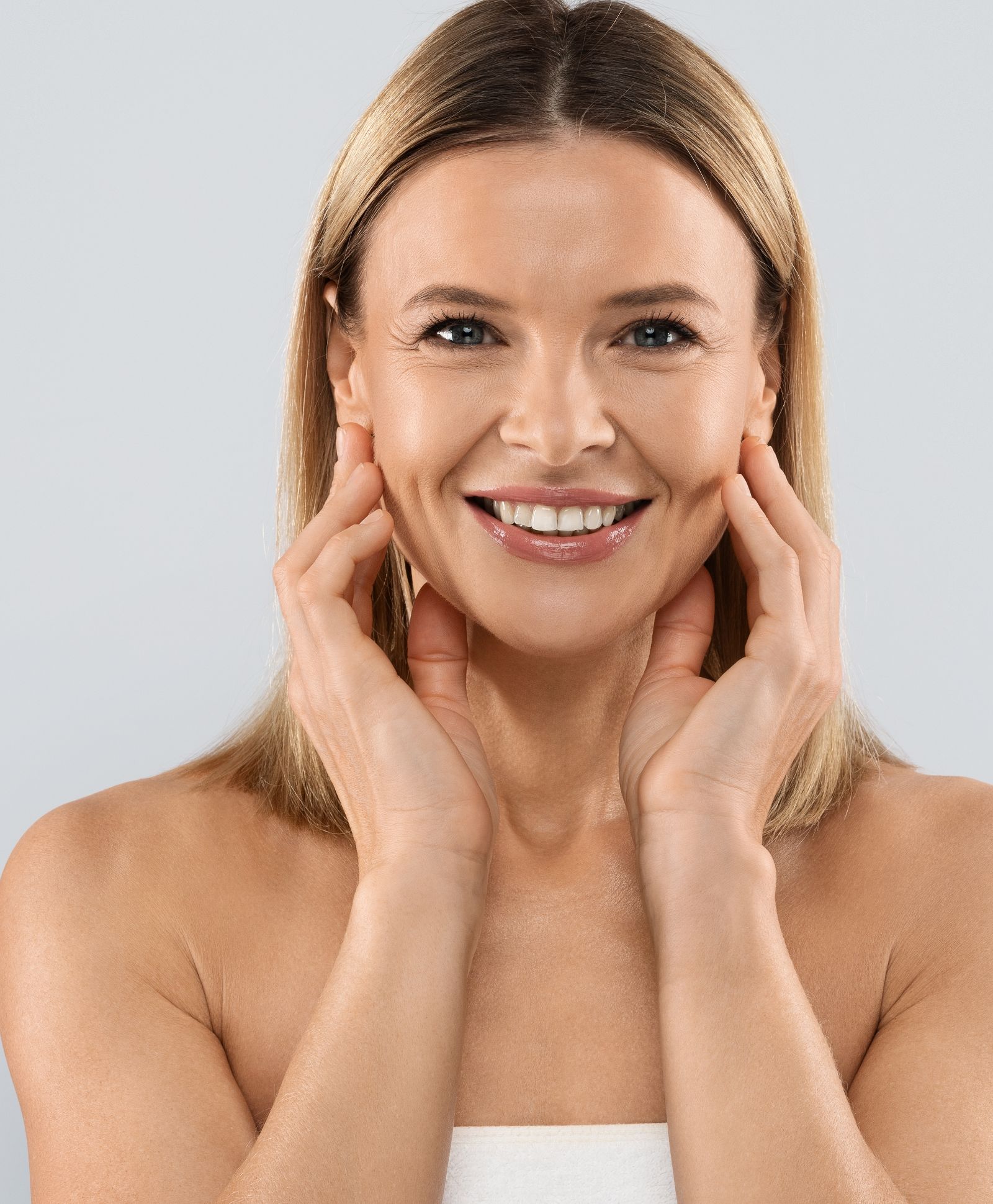 Smiling woman touching her face after PRP injections for skin rejuvenation, showing smooth and radiant results.