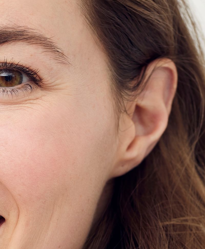Close-up of a woman’s face showing smooth skin, faint crow’s feet near the eye, and natural complexion.
